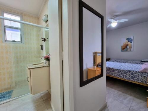 ein Bad mit einem Bett und einem Spiegel im Zimmer in der Unterkunft Apartamento em Pitangueiras! 70m da praia! Lindo e Aconchegante ! in Guarujá