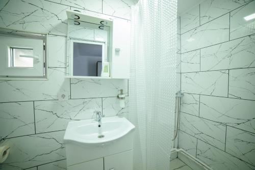 a white bathroom with a sink and a mirror at Cabana de Sub Deal Arieșeni in Arieşeni