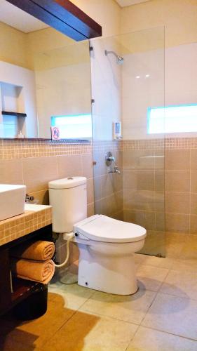 a bathroom with a toilet and a glass shower at Maya Kori Villa in Jimbaran