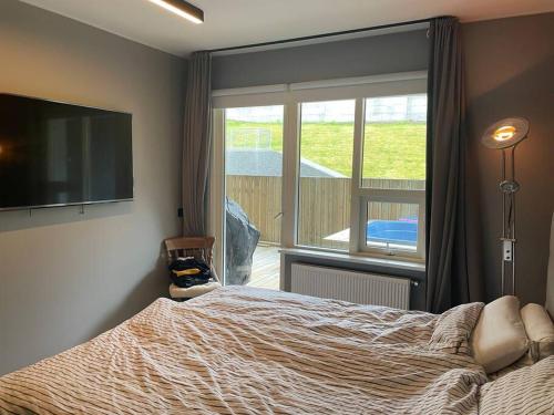 a bedroom with a bed and a large window at Bright beautiful flat on hilltop w hot tub in Hafnarfjördur