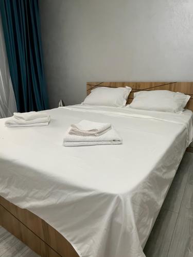 a large white bed with two towels on it at JK ALTUNBULAK in Almaty