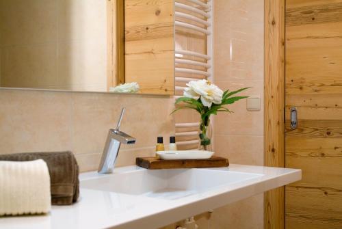 ein Badezimmer mit einem Waschbecken und einer Vase aus Blumen in der Unterkunft Das Bäckergut am Haldensee in Haldensee