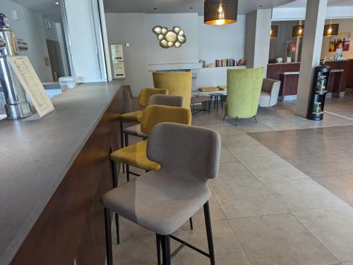a bar with yellow and gray chairs at a counter at Logis De La Loire - Restaurant Les Bateliers in Ancenis