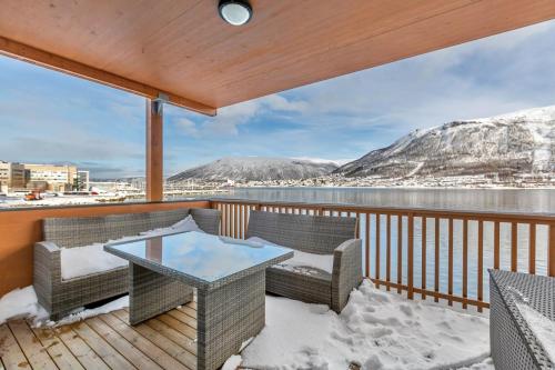 a balcony with wicker chairs and a glass table at Seaside city appartment in Tromsø