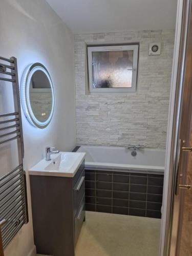 ein Badezimmer mit einem Waschbecken, einer Badewanne und einem Spiegel in der Unterkunft Cosynitebnb for 4 in Birmingham