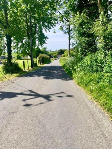 an empty road with trees on the side of it at Quiet Farm Cottage Enniskillen Fermanagh in Enniskillen