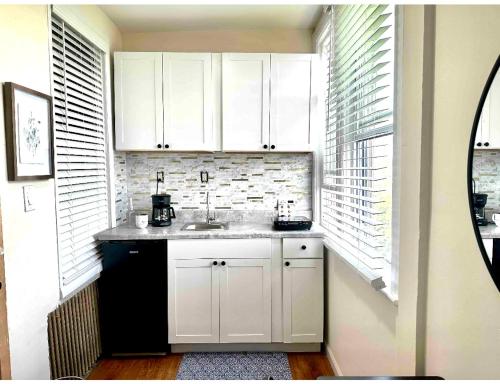 eine Küche mit weißen Schränken, einem Waschbecken und einem Fenster in der Unterkunft 0-A Diamond in Yonkers, NY in Yonkers