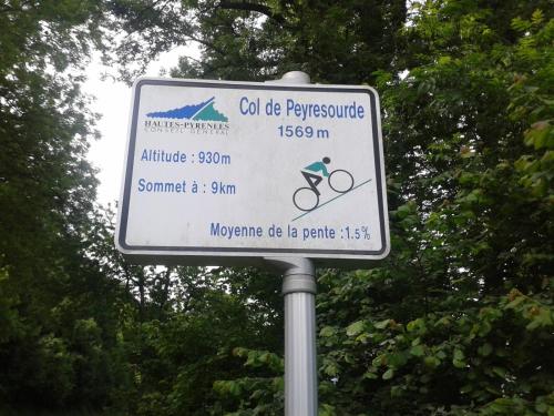 a street sign on a pole in front of trees at Hôtel du Val d'Aure in Cadéac