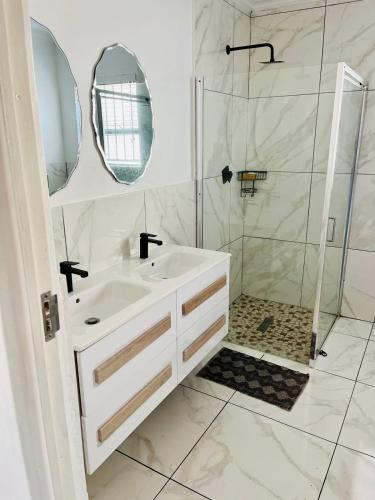 a white bathroom with a sink and a shower at Petalsoft in Pretoria