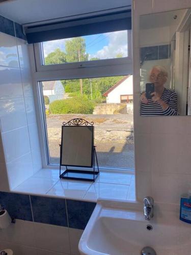 a woman taking a picture of a mirror in a bathroom at Aberlour Apartment 92 B in Aberlour