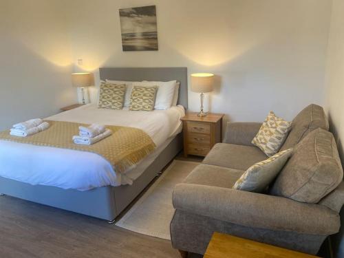 a bedroom with a bed and a couch and a chair at Aberlour Apartment 92 B in Aberlour