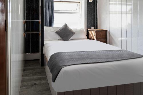 een bed in een kleine kamer met een raam bij OYO Harlands Hotel in Blackpool