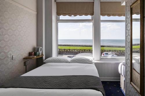 a bedroom with a bed and a window with the ocean at OYO Harlands Hotel in Blackpool