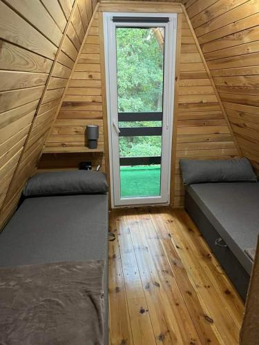 a small room with two beds and a window at Chatka pod lasem in Jarnołtówek