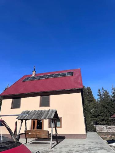 ein Haus mit rotem Dach und Sonnenkollektor in der Unterkunft Casă de vacanță în zona montană in Sântimbru-Băi