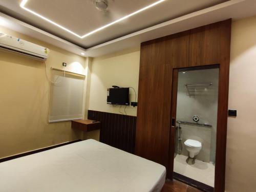 a bedroom with a bed and a toilet and a television at HOTEL B S HEIGHTS in Deoghar