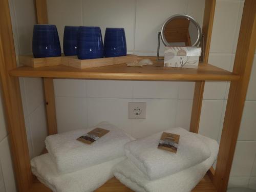 a shelf with blue glasses and towels and a mirror at Ferienwohnung Wohlleben Gbr in Simmerath
