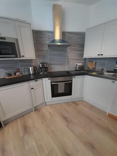uma cozinha com armários brancos e piso em madeira em Flat 5 Corner House 1 bedroom em Doncaster