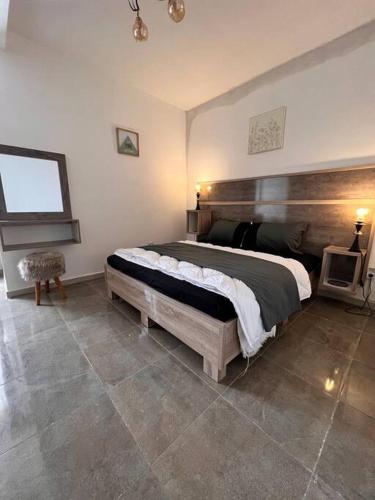 - une chambre avec un grand lit et une tête de lit en bois dans l'établissement RESIDENCE IGHIL ELBORDJ, à Béjaïa