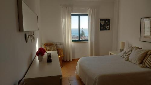 a white bedroom with a bed and a window at Casa da Encosta in Ericeira