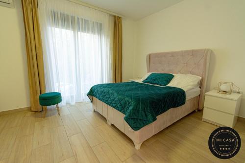 a bedroom with a bed with a green blanket and a window at Mi Casa 2 in Vrdnik