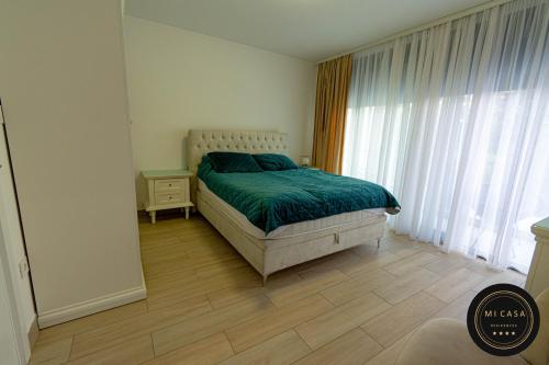 a bedroom with a bed with a green comforter at Mi Casa 2 in Vrdnik