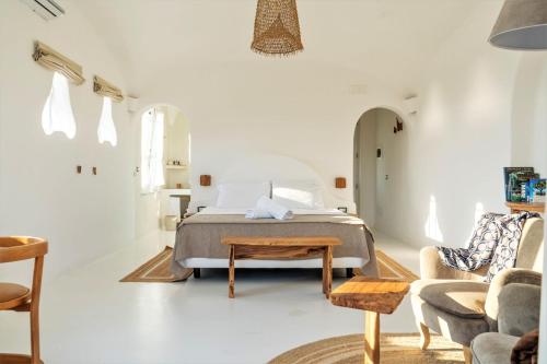 a white bedroom with a bed and a chair at Villa Ravino Secret Retreat in Ischia