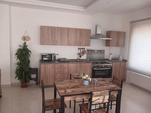 Il comprend une cuisine avec une table et des chaises en bois. dans l'établissement Zara's luxury Home- central location near Abdali, à Amman