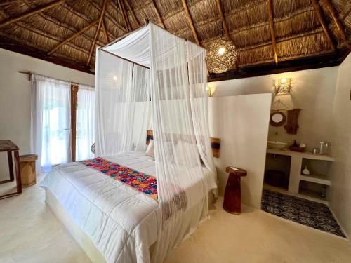 een slaapkamer met een bed met een hemelbed bij Lodge Tzunum Jade in Tulum