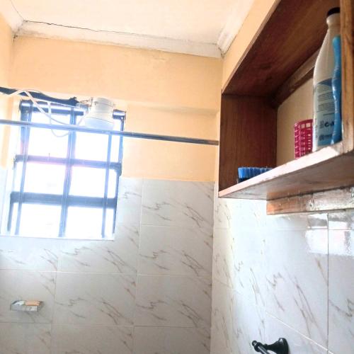 La salle de bains est pourvue d'une fenêtre et d'un comptoir en marbre. dans l'établissement Milly's homes, à Kakamega