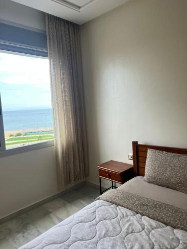 um quarto com uma cama e uma janela com o oceano em Recidence montblanc Tanger em Tânger