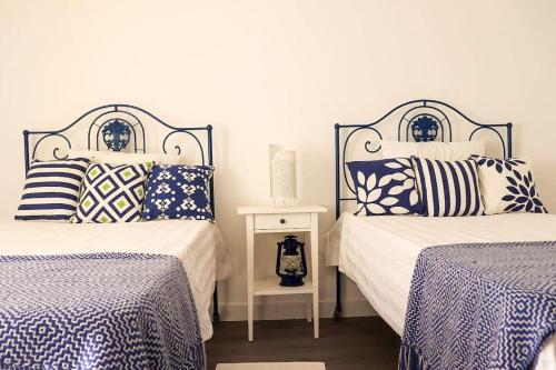 a bedroom with two beds with blue and white pillows at Cozy&Charming Naz in Nazaré