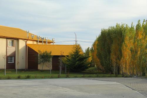 a building with a yellow roof next to a parking lot at Hotel Picos Del Sur in El Calafate