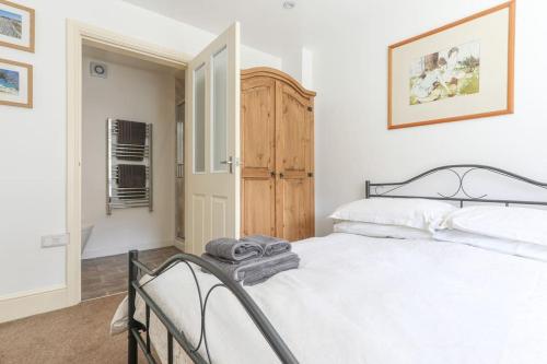 a bedroom with a white bed and a wooden cabinet at Wend Gardens, Carleton, Skipton. Pet friendly. in Skipton