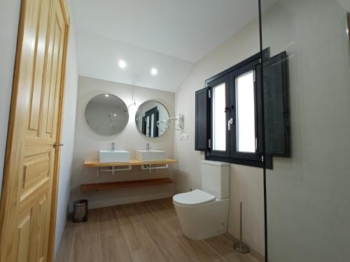 a bathroom with two sinks and a toilet and a mirror at CASA LA GRANJA in Galizano