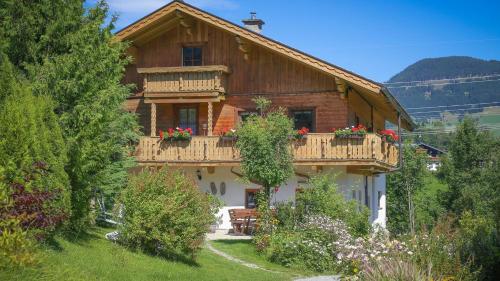 uma casa de madeira com uma varanda com flores em Landhaus Sommerbichl em Embach