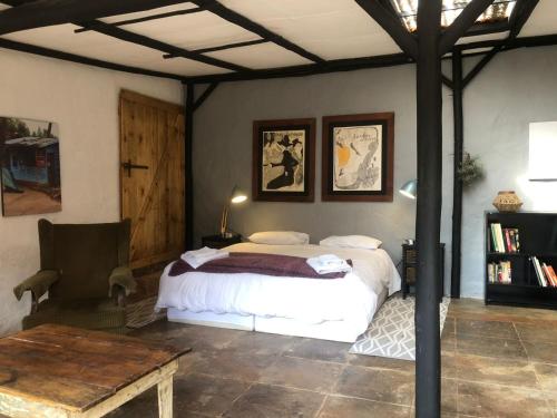 a bedroom with a large bed and a table at Mill Lane Farmhouse in Hartbeespoort