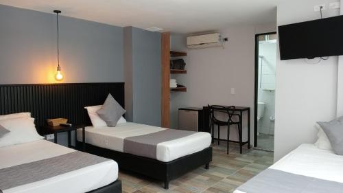 Habitación con 2 camas, mesa y TV. en Hotel Palmas del Estadio en Medellín