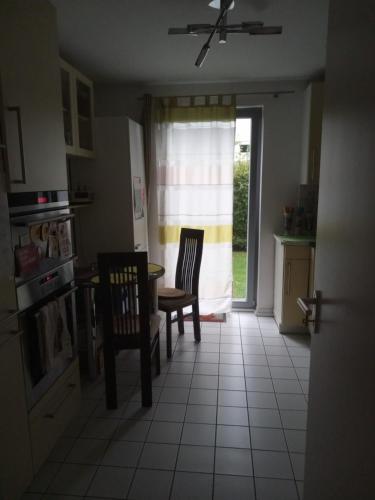 eine Küche mit 2 Stühlen, einem Tisch und einem Fenster in der Unterkunft Ferienwohnung in München