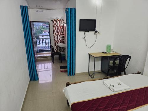 Habitación con cama, escritorio y TV. en Cicily Holidays Inn, en Munnar