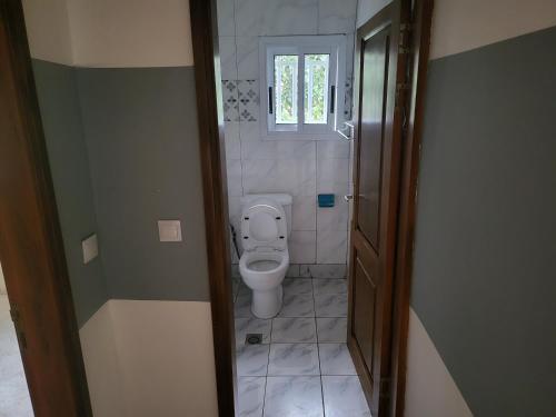 a bathroom with a toilet and a window at MediSweet Apartments Meublés in Yaoundé