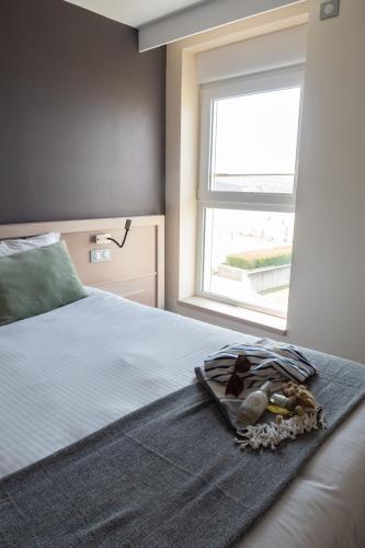 a bedroom with a bed with a window and a blanket at Hôtel de la Baie des Trépassés in Plogoff