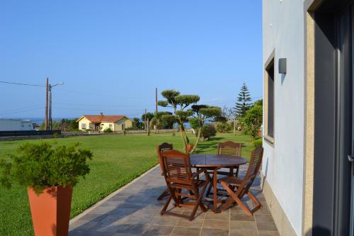 un patio con mesa, sillas y un campo en Casa Patricia, en Pontevedra