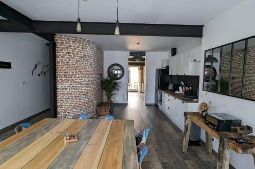 una cucina e una sala da pranzo con tavolo e muro di mattoni di Chez Pépère a Londinières