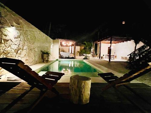 a swimming pool with two chairs next to a building at Lodge Tzunum Jade in Tulum