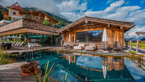 uma casa com piscina em frente a um edifício em Alpinhotel Berghaus spa em Tux