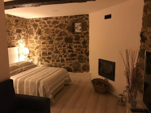 a bedroom with a bed and a stone wall at CASA DO REI, PADERNE (FERREIRA DE PANTÓN) in Ferreira de Panton