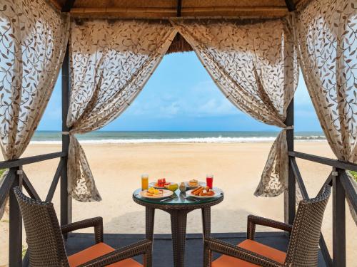 - une table et des chaises sur la plage donnant sur l'océan dans l'établissement ITC Grand Goa, a Luxury Collection Resort & Spa, Goa, à Utorda