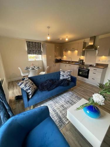 a living room with a blue couch and a kitchen at Luxurious Apartment in Brooklands in Milton Keynes