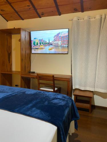 - une chambre avec un lit et une télévision murale dans l'établissement Pousada Antígona, à Parati